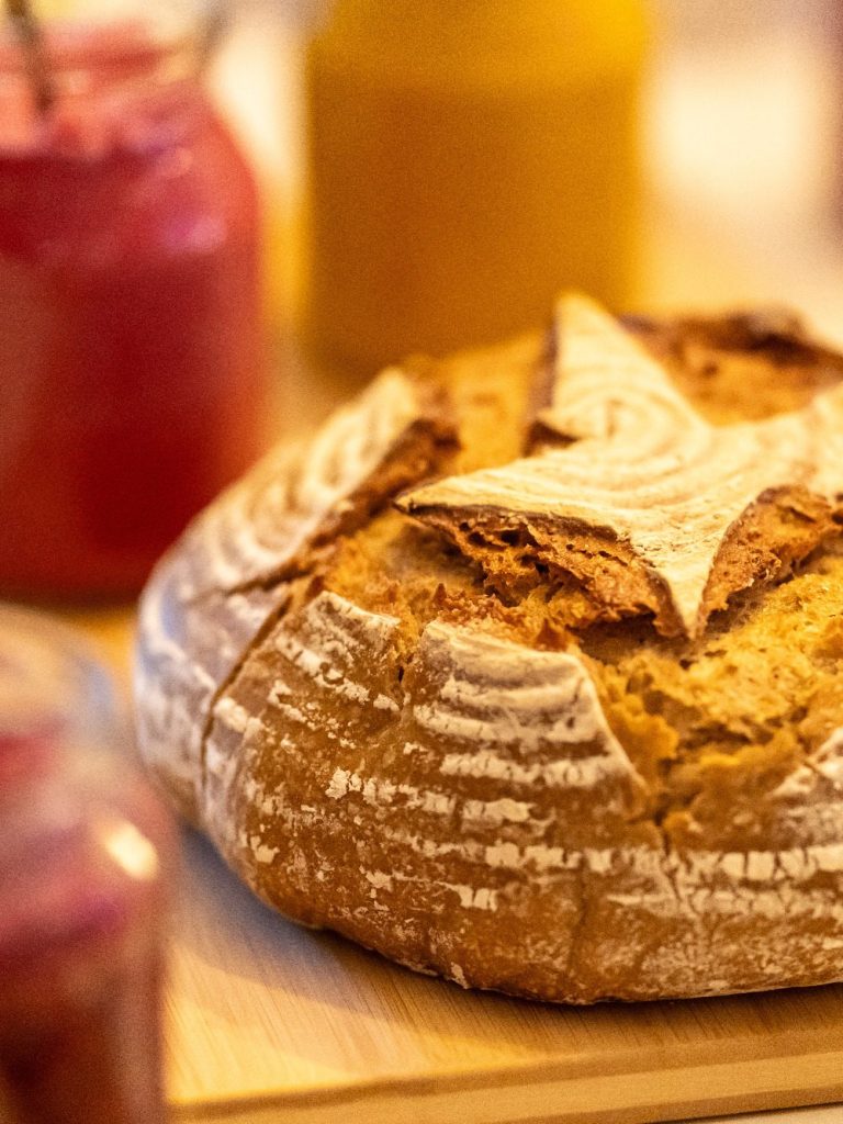 ein Sauerteigbrot mit einem Stern und rotem Aufstrich im Glas daneben